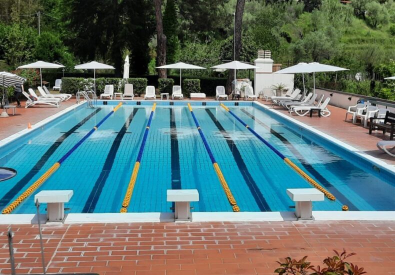 Corsie della piscina scoperta con blocchi di partenza, ombrelloni e lettini