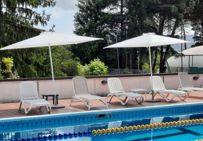 Piscina estiva circondata da alberi e spazi per il relax