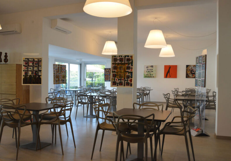 Tavoli della sala ristorante sotto le luci a sospensione, con richiami al tennis alle pareti
